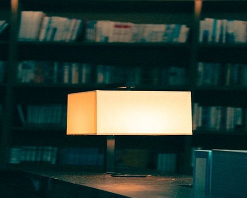 A warm desk lamp illuminating a book in a dark room