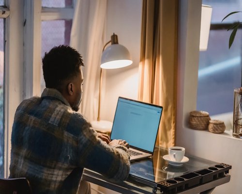 Person adjusting laptop screen to avoid window glare